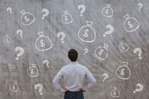 Man looking at chalkboard with drawings of moneybags