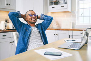 Relaxed man holding his hands behind his head in front of his laptop