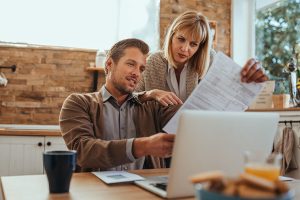 Couple looking at tax documents together in front of a laptop