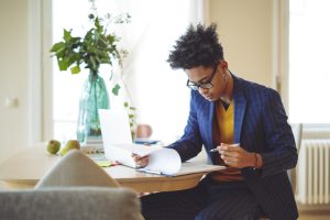 Young professional looking as a clipboard with documents while sitting at a table