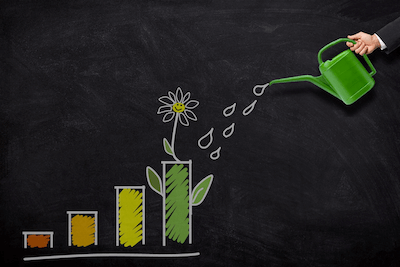 chalkboard drawing of a bar graph with the tallest, most right column topped with a flower with a hand watering it