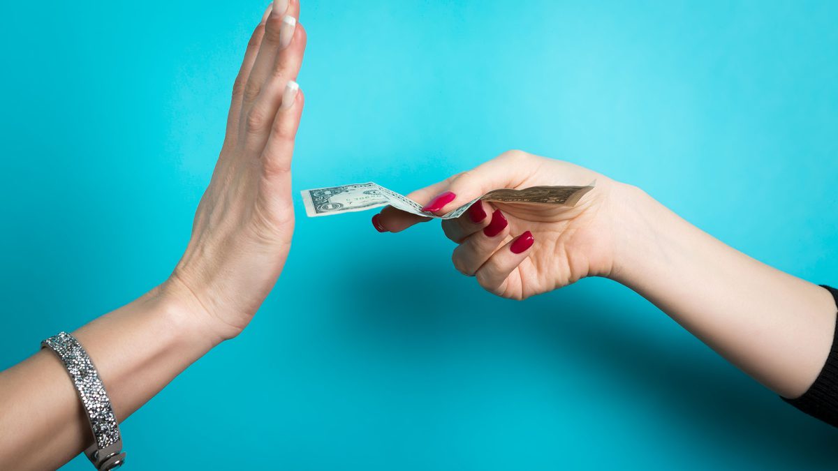 One hand holding out a dollar bill and another hand making a stop motion sign above a turquoise background