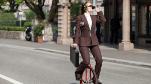Woman Drinking coffee while holding briefcase on unicycle