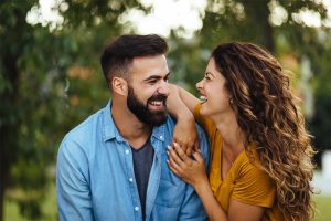 Happy couple smiling at each other outside in a lush landscape