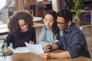 3 young adults looking at documents