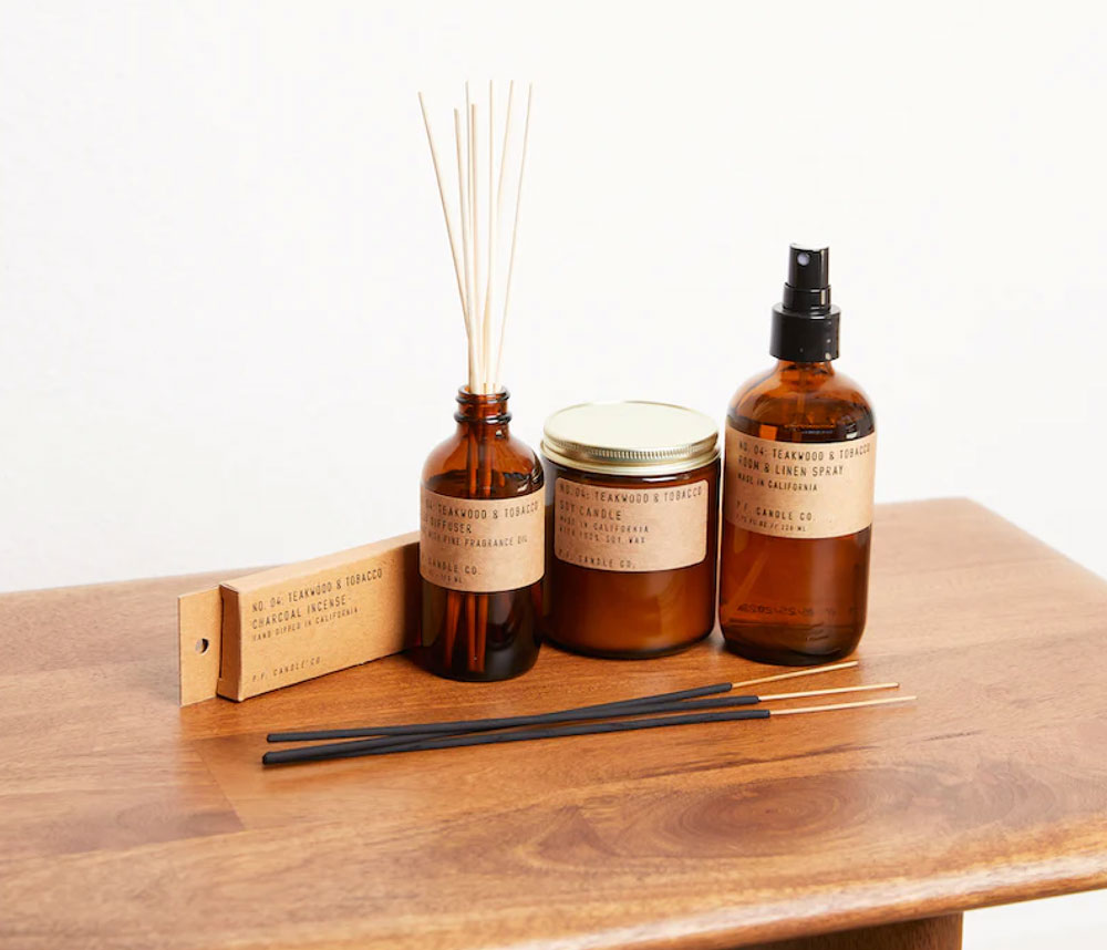 Aromatherapy bundle of burning sticks, spray, and lotion sitting on a wood desk with a sepia look