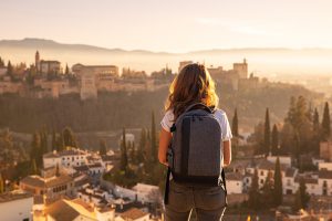 Silhouette of a woman backpacking on top of a high view of a cityscape