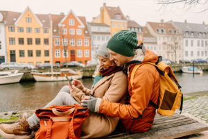 Couple traveling in winter on a canal while looking at a phone together