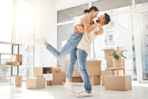 Smiling couple hugging in a room with moving boxes
