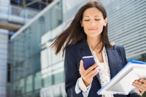 Business woman using cell phone outside office