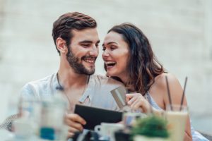 Couple smiling and holding credit card and tablet