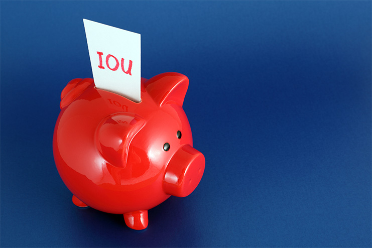 I.O.U. paper sticking out of red piggy bank