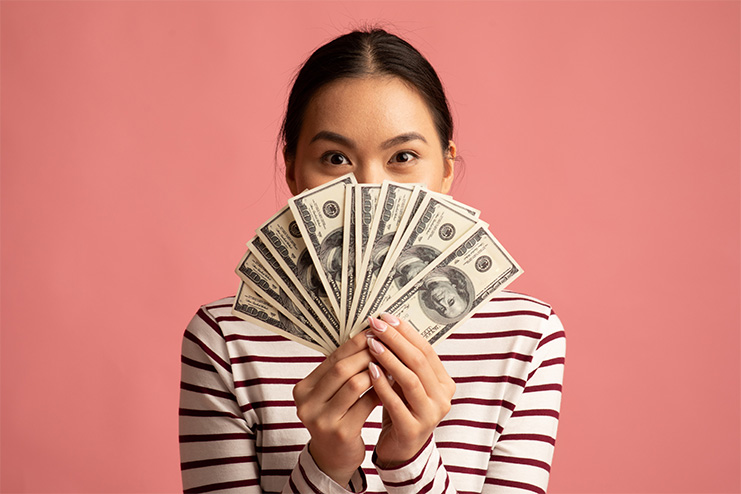 millennial woman holding a fanned out stack of U.S. cash
