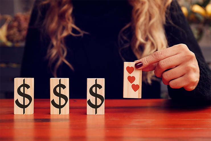 person lining up vertical blocks with money and heart symbols