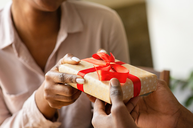 two people holding one gift-wrapped box