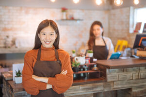 Woman wearing apron with arms crossed in business