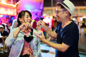 Couple eating street food together outside at night