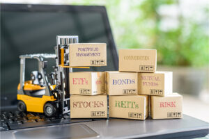 Toy forklift on top of a laptop keyboard that's lifting cardboard boxes labeled with different investment types