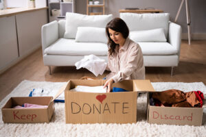 Woman sorting donations, discard, and keep piles.