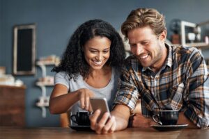 Couple smiling while pointing to mobile phone screen