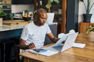 Man using calculator in front of laptop