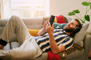 Man wearing headphones while laying on a couch