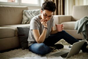 Woman sitting on floor with laptop and papers