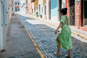 A beautiful woman strolling along the streets of Old San Juan, with the blue-toned cobblestone streets.