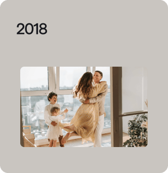 2018 photo of family of 4 hugging outside large window
