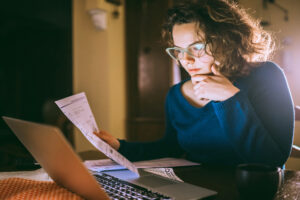 Women wearing blue top while looking at laptop.