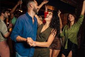 Couple dancing while smiling among others