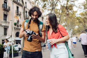 Young man showing captured image to woman wearing red top