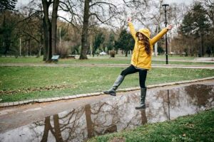 Woman in raincoat playing in puddles