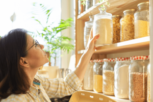 Mature woman in the kitchen pantry with products.