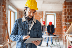 Hispanic Construction Worker Using Digital Tablet At Site.