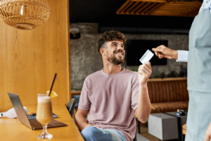 Happy man paying the bill in a café with a credit card.