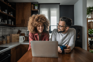 Happy couple using laptop at home.