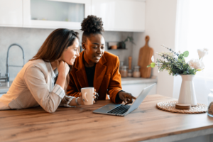 Two multiethnic female friends online shopping from home.