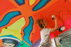 Mid adult Iranian woman artist painting mural inside party bus