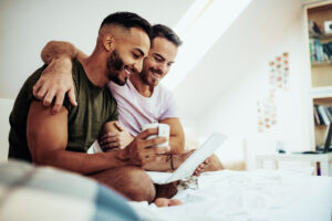 Two men smiling as they look at a shared laptop.